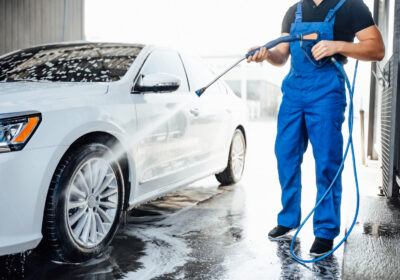 professional-washer-blue-uniform-washing-luxury-car-with-water-gun-open-air-car-wash